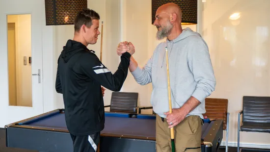 Begeleider en bewoner bij de pooltafel